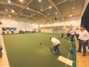 A member delivering a bowl on the indoor carpet green