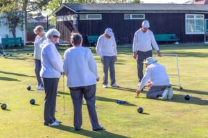 A group of seven members in whites walking across the outdoor green