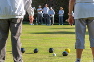 Close-up view of bowls on the grass and a player's legs and feet in position during a game